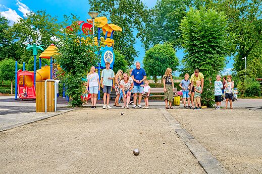 Familia jugando a la petanca cerca de un parque infantil en el camping CAPFUN Heino en Heino.