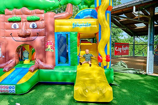 Nińo en tobogán hinchable gigante en el camping CAPFUN Heino en Heino.
