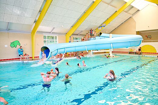 Piscina cubierta con tobogán acuático y bañistas en el camping CAPFUN Heino en Heino.