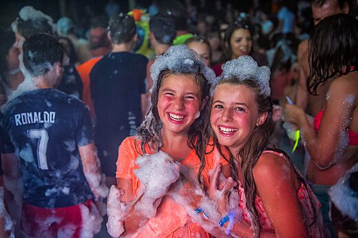 Dos niñas sonrientes disfrutan de una animada fiesta de la espuma en el camping CAPFUN Heino en Heino.