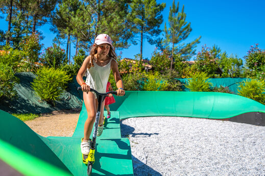 Niño en patinete en pump track en el camping CAPFUN Huttes en Saint-Denis d'Oléron.