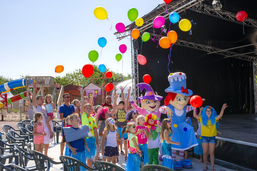 Niños y mascotas lanzando globos de colores en una animación en el camping CAPFUN Huttes en Saint-Denis d'Oléron (17).