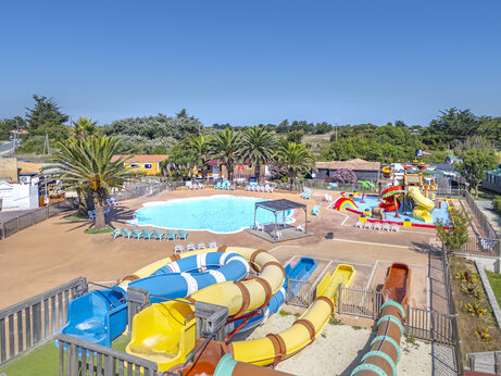 Toboganes acuáticos coloridos y piscina exterior en el camping CAPFUN Huttes en Saint-Denis d'Oléron.