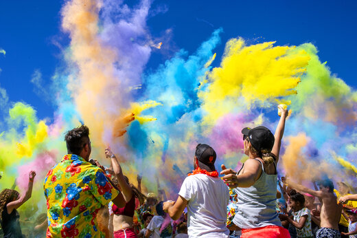 Animación festiva con polvos de colores y participantes alegres en el camping CAPFUN Huttes.