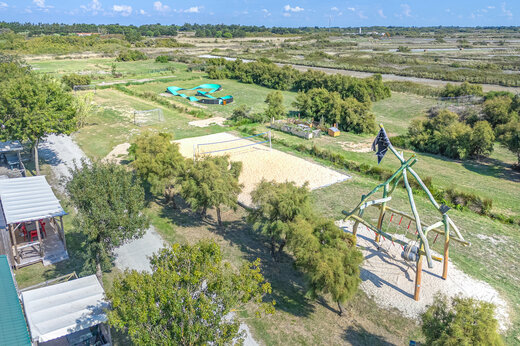 Parque infantil de madera, cancha de voleibol y pumptrack en el camping CAPFUN Huttes en Saint-Denis d'Oléron.