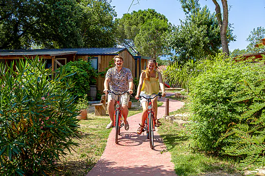 Pareja sonriente en bicicleta por camino del camping CAPFUN Mael en ARGELES. Pareja sonriente en bicicleta por camino del camping CAPFUN Mael en ARGELES.