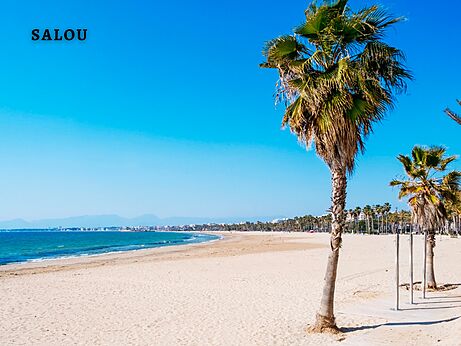 Playa de arena fina de Salou con palmeras, una ciudad para visitar en Cataluña.